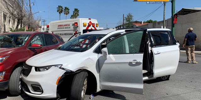 A member of the Mexican security forces stands next to a white minivan with North Carolina license plates and multiple bullet holes, at the crime scene where gunmen kidnapped four US citizens who entered Mexico from Texas, Friday, March 3 2023. 