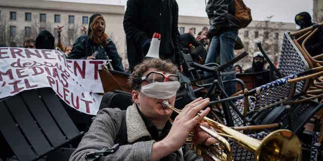 Un hombre toca la trompeta frente a una barricada durante una manifestación en Lyon, Francia, el 7 de marzo de 2023. 