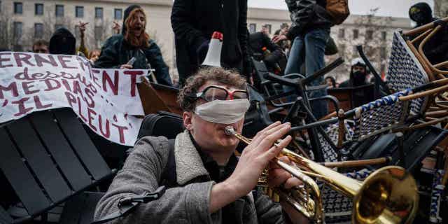 Los trabajadores franceses siguen organizando huelgas para protestar contra el plan de Macron para reformar el sistema de pensiones 4 Un hombre toca la trompeta frente a una barricada durante una manifestación en Lyon, Francia, el 7 de marzo de 2023.
