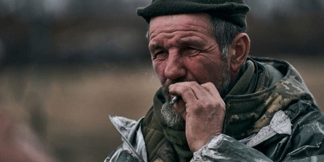 A Ukrainian soldier smokes at the front line near Bakhmut, Ukraine, Tuesday, March 7, 2023.