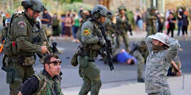 Albuquerque police detain members of the New Mexico Civil Guard, an armed paramilitary group, following the shooting of a man during a protest over a statue of Spanish conquerer Juan de Oñate on June 15, 2020, in Albuquerque, New Mexico.