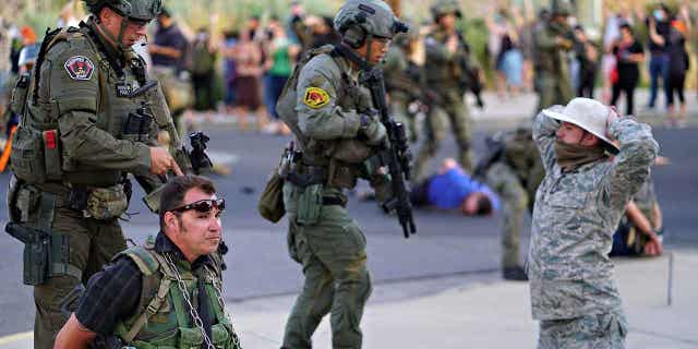 Albuquerque police detain members of the New Mexico Civil Guard, an armed paramilitary group, following the shooting of a man during a protest over a statue of Spanish conquerer Juan de Oñate on June 15, 2020, in Albuquerque, New Mexico.