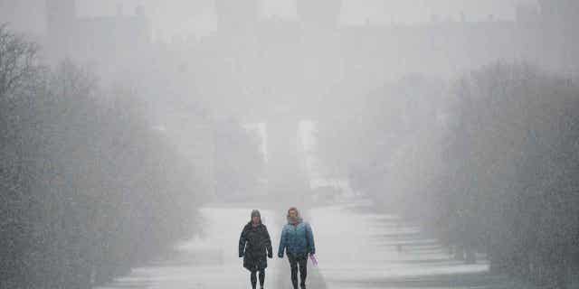 People walk under the snow towards Windsor Castle, Berkshire, on March 8, 2023. Parts of the U.K. woke up to snow on Wednesday.