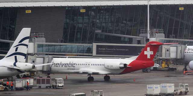 Baggage carts make their way past a Helvetic Airways' aircraft from which about $50 million worth of diamonds were stolen on the tarmac of a Brussels airport on Feb. 19, 2013. The four remaining suspects in the case were acquitted on appeal on March 8, 2023, leaving it unclear whether the mastermind will ever be found. 