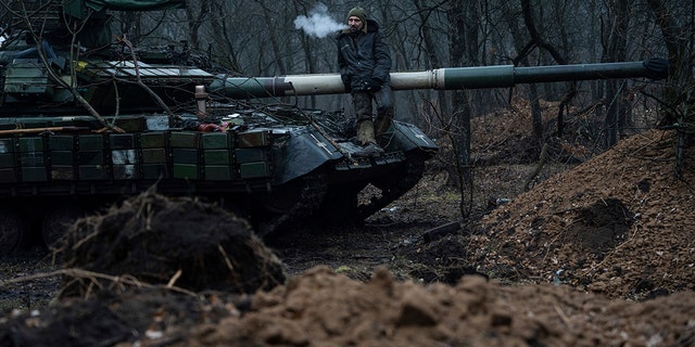 A Ukrainian serviceman smokes a cigarette while standing on the tank near Bakhmut, Ukraine on Wednesday, March 8, 2023. 
