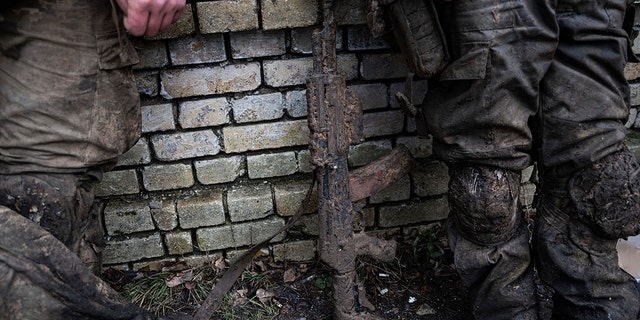 A mud-stained handgun in front of Ukrainian servicemen who have just returned from Bakhmut's tranches in Chasiv Yar, Ukraine on Wednesday, March 8, 2023. 