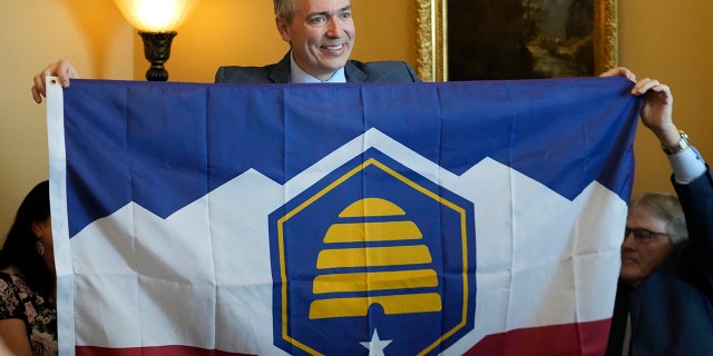 Utah Sen. Dan McCay, R-Riverton, unfurls the state's new flag during a Senate media availability on Thursday, March 2, 2023, in Salt Lake City. 