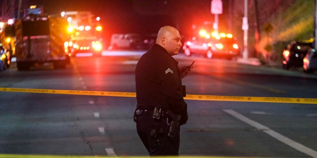 A police officer stands guard near the crime scene where three LAPD officers were shot and killed on Wednesday, March 8, 2023 in Los Angeles. 