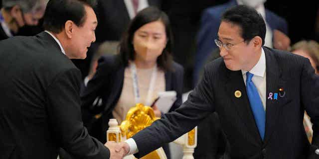 Japan's Prime Minister Fumio Kishida, right, shakes hands with South Korea's President Yoon Suk Yeol in Cambodia, on Nov. 13, 2022. The leaders of the two countries will hold a summit next week,