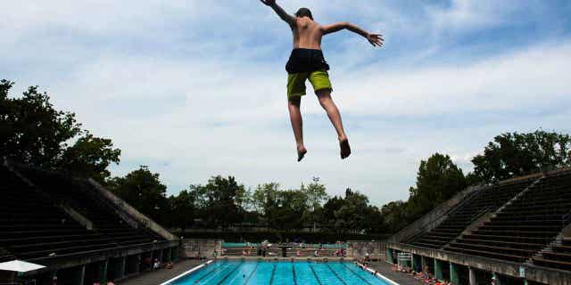 A boy jumps into the water at the Olympic open air public pool in Berlin, Germany, on May 21, 2014. Women in Berlin will be allowed to go topless at the city's public pools soon.