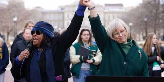 Michigan Rep. Brenda Carter, left, and state Sen. Rosemary Bayer join hands during a news conference to call for gun reform on Feb. 20, 2023, in Lansing, Michigan. Democrats in the state are planning to bring an 11-bill package to the Legislature next week aimed at changing gun laws.