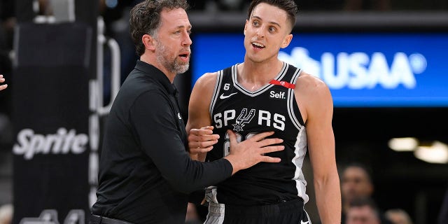 Zach Collins, de los San Antonio Spurs, a la derecha, es sujetado por el entrenador asistente de los Spurs, Matt Nielsen, después de un altercado en la cancha durante la segunda mitad de un partido de baloncesto de la NBA contra los Denver Nuggets, el viernes 10 de marzo de 2023, en San Antonio. 