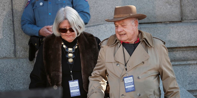 FILE - Former U.S. Rep. Pat Schroeder, D-Colo., left, and her husband, Jim, head to their seats to watch the inauguration ceremony for Colorado Gov. Jared Polis on Jan. 8, 2019, in Denver. 