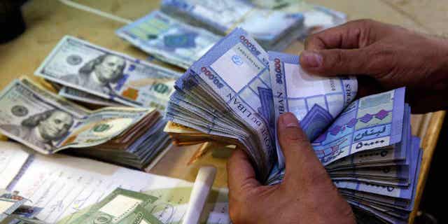 A man counts Lebanese pounds at an exchange shop in Beirut, Lebanon, on Aug. 20, 2018. Lebanon's currency hit a new low on March 14, 2023, trading at an unprecedented 100,000 Lebanese pounds to the dollar on the black market.