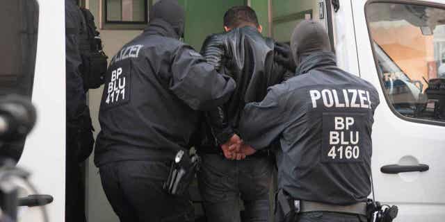 Police officers arrest a man during a raid in Berlin, Germany, on March 15, 2023. German police conducted a raid against a group of suspected human smugglers.