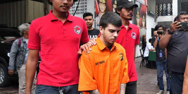 Police officers escort Brazilian national Gustavo Pinto da Silveira prior to a press conference in Jakarta, Indonesia, on March 15, 2023. Indonesian authorities arrested four foreigners who allegedly tried to smuggle drugs into the country.