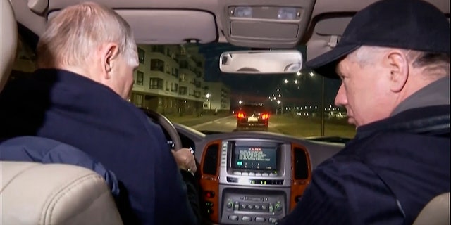 Russian President Vladimir Putin, left, and Russian Deputy Prime Minister Marat Khusnullin drive a car during their visit to Mariupol.  Putin traveled to Crimea to mark the ninth anniversary of Ukraine's annexation of the Black Sea peninsula.