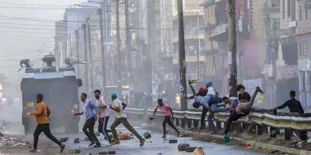 Protesters stumble as they flee from a police water cannon in the Eastleigh neighborhood of Nairobi, Kenya, on March 20, 2023. 