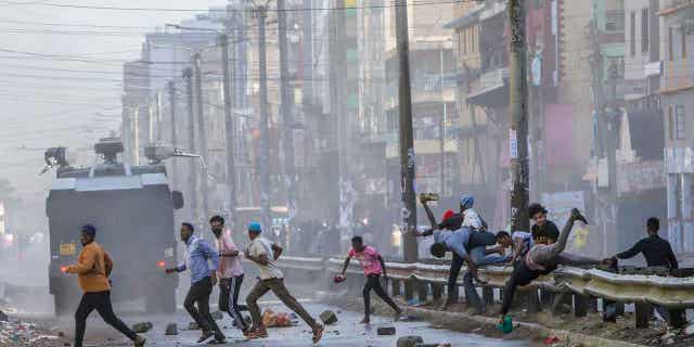 Protesters stumble as they flee from a police water cannon in the Eastleigh neighborhood of Nairobi, Kenya, on March 20, 2023.