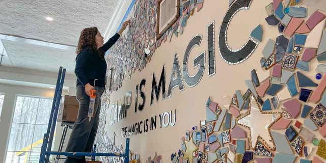 Artist Mia Schon finishes a mural in one of the activity rooms of the Hole In the Wall Gang Camp on March 2, 2023, in Ashford, Connecticut. Two years after a fire destroyed Paul Newman's camp for seriously ill children, the rebuilt camp center is opening. 