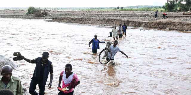 People walk through floodwaters in the aftermath of Tropical Cyclone Freddy in southern Malawi on March 18, 2023. During a conference in the Ethiopian capital of Addis Ababa on March 20, 2023, leaders of African countries discussed finance options that would allow for the forgiveness of debt in exchange for investment in green energies.