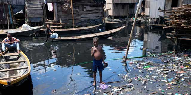 A child stands in dirty water surrounded by rubbish in Nigeria's economic capital Lagos in March.  20, 2023. March 22 is World Water Day, established by the United Nations and celebrated annually since 1993 to raise awareness of access to clean water and sanitation.  Many children in Africa lack access to clean drinking water.