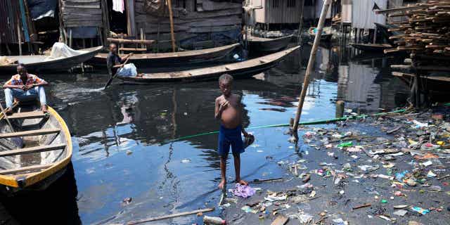 A child stands in dirty water surrounded by rubbish in Nigeria's economic capital Lagos in March.  20, 2023. March 22 is World Water Day, established by the United Nations and celebrated annually since 1993 to raise awareness of access to clean water and sanitation.  Many children in Africa lack access to clean drinking water.