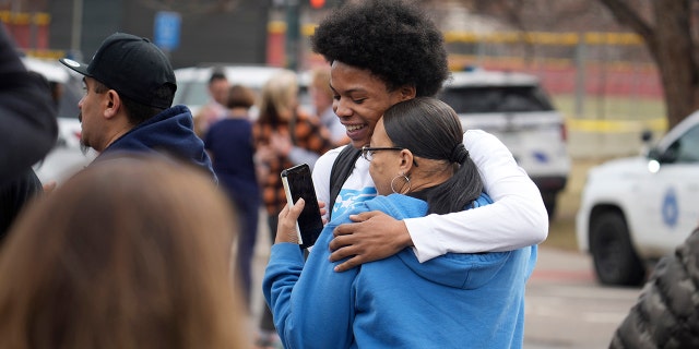 A student, rear, hugs a woman as they reunite following a shooting at East High School, Wednesday, March 22, 2023, in Denver. Authorities say two school administrators were shot and wounded after a handgun was found during a daily search of a student at the Denver high school. 
