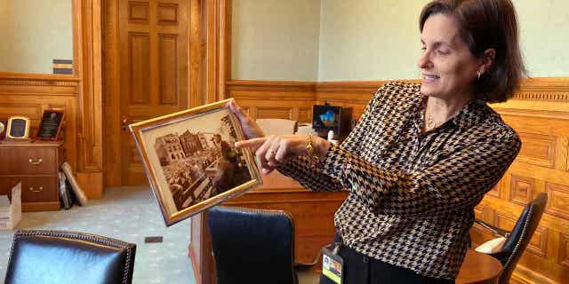 New Jersey Treasurer Elizabeth Muoio shows a photograph of former President John F. Kennedy on March 22, 2023, in Trenton, New Jersey, speaking at the statehouse building from roughly just outside the spot where her new office is located. The building has been reopened and reoccupied by the governor and his administration following a nearly six year, $300-million renovation.