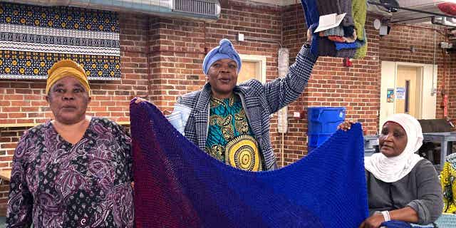 Mochozi Bigelegele, left, and Martha Mlebinge, center, both originally from Congo, and Fatuma Hussein, right, originally from Burundi, hold handmade blankets they picked out at a Welcome Blanket giveaway event on March 21, 2023, in Burlington, Vermont.