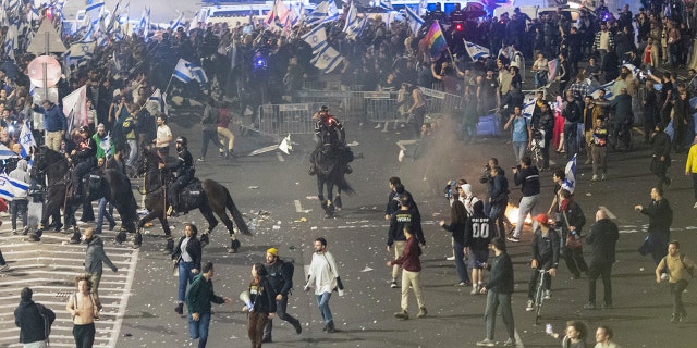 Israeli police disperse demonstrators blocking a highway during a protest against plans by Prime Minister Benjamin Netanyahu's government to overhaul the judicial system in Tel Aviv, Israel, Monday, March 27, 2023. 