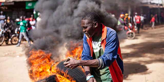 Un manifestante reacciona junto a una barricada en llamas durante una manifestación convocada por Raila Odinga por el alto costo de la vida en Nairobi, el 27 de marzo de 2023. La policía de Kenia se prepara para la segunda ronda de protestas antigubernamentales organizadas por la oposición.  El gobierno lo calificó de ilegal.
