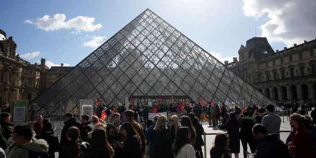 El museo del Louvre de Francia está cerrado al público después de que los manifestantes por la reforma de las pensiones bloquearan la entrada 4 Los visitantes esperan mientras los manifestantes marchan frente al Museo del Louvre el 27 de marzo de 2023 en París. El presidente Emmanuel Macron ha enojado al público al enviar su ya impopular plan para aumentar la edad de jubilación en dos años a través del Parlamento sin votación.