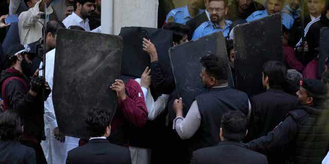 Security personnel with bulletproof shields escort former Prime Minister Imran Khan, center, as he arrives at a courthouse in Islamabad, Pakistan March 27, 2023. A Pakistani court ruled in Khan's defense on Monday.