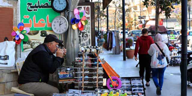El primer ministro libanés se retracta de su decisión de posponer el inicio del horario de verano 4 Un vendedor ambulante libanés que vende y repara relojes, se sienta junto a dos relojes que muestran diferentes horas en el Líbano, el 27 de marzo de 2023. El primer ministro interino del Líbano revierte la decisión de retrasar el inicio del horario de verano en un mes.