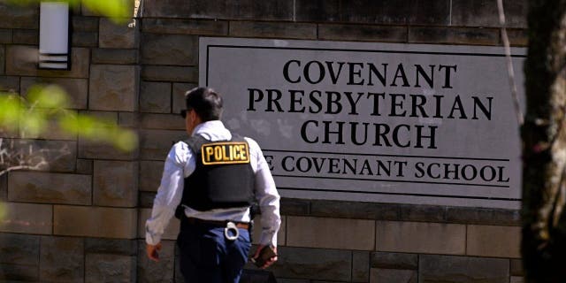 A police officer walks by an entrance to The Covenant School after a shooting in Nashville, Tennessee, on Monday, March 27, 2023. 