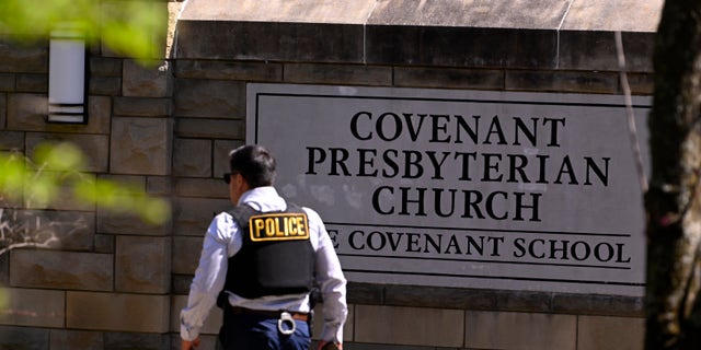 A police officer walks by an entrance to The Covenant School after a shooting in Nashville, Tennessee, on Monday, March 27, 2023.