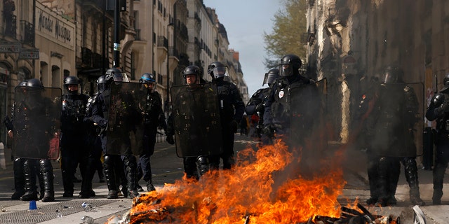 Riot police officers stand behind a street fire during a demonstration Tuesday, March 28, 2023, in Nantes, western France. 