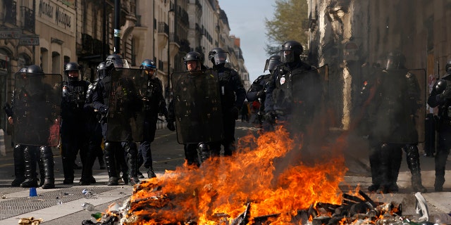 Riot police officers stand behind a street fire during a demonstration Tuesday, March 28, 2023, in Nantes, western France. 