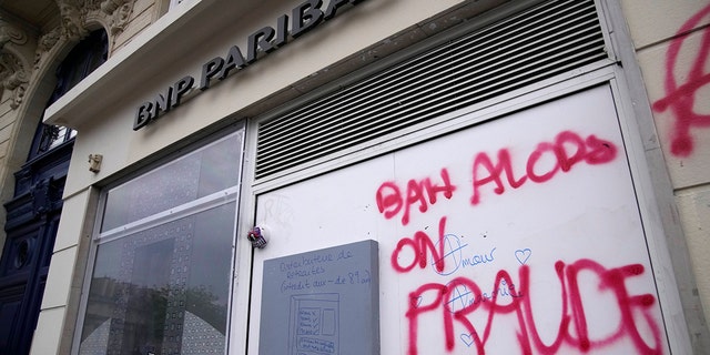 Graffiti says "So, you fraud" during a demonstration against a pension reform Tuesday, March 28, 2023, in Paris. Authorities raided the Paris offices of five banks Tuesday on suspicion of tax fraud, French prosecutors said.
