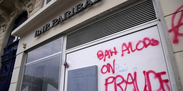 Graffiti says "So, you fraud" during a demonstration against a pension reform Tuesday, March 28, 2023, in Paris. Authorities raided the Paris offices of five banks Tuesday on suspicion of tax fraud, French prosecutors said.