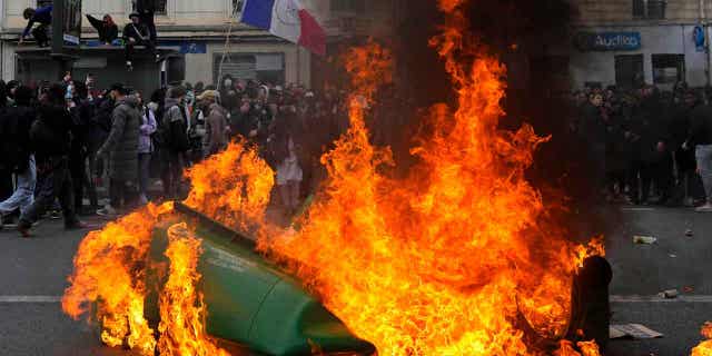 Demonstrators walk past burning garbage cans during a demonstration on March 28, 2023, in Paris. Sanitation workers in Paris will return to work on Wednesday as the protests seem to be calming down.