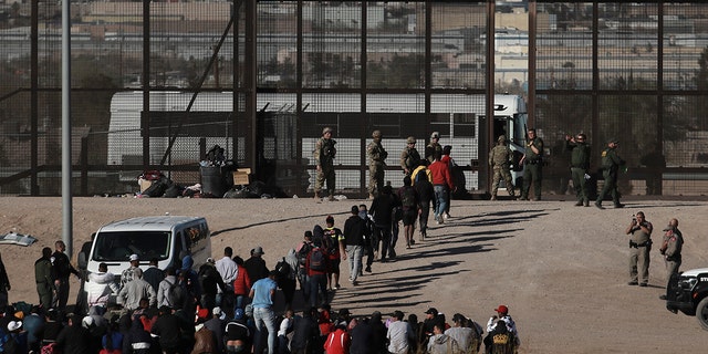 Migrants walk into U.S. custody after crossing the border from Ciudad Juarez, Mexico, Wednesday, March 29, 2023.