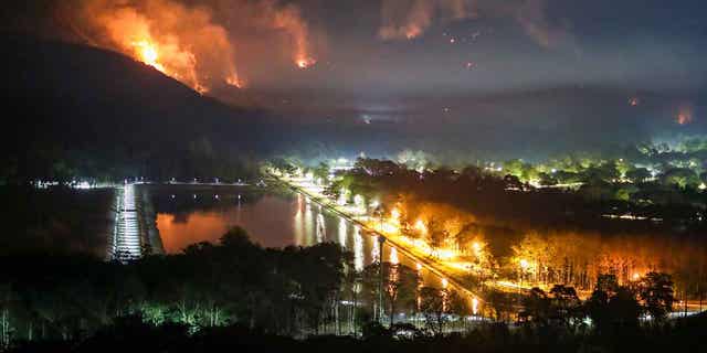 El fuego y el humo salen de un incendio forestal en la provincia de Nakhon Nayok, Tailandia, el 30 de marzo de 2023. El fuego envolvió grandes áreas de dos montañas el jueves.