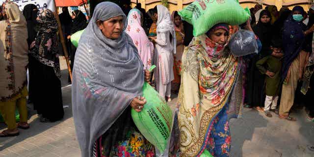 Women leave while others wait their turn to get a free sack of wheat flour at a distribution point in Lahore, Pakistan, on March 30, 2023. The country's government is providing flour to poor families during Ramadan due to high inflation in the country. 