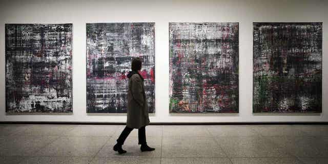 A woman walks past paintings by Birkenau at a new exhibition of artworks created by Gerhard Richter at the Neue Nationalgalerie museum in Berlin, Germany, March 31, 2023. 