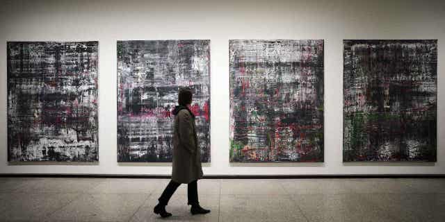 A woman walks past paintings by Birkenau at a new exhibition of artworks created by Gerhard Richter at the Neue Nationalgalerie museum in Berlin, Germany, March 31, 2023. 