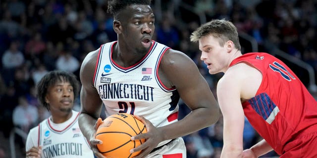 U-Adama Sanogo (21) waseConnecticut ubukeka edlula ngemuva kokuphinda abhekane no-St. Mary's Mitchell Saxen (11) engxenyeni yokuqala yomdlalo we-basketball wasekolishi womzuliswano wesibili ku-NCAA Tournament, ngeSonto, Mashi 19, 2023, e-Albany, NY.