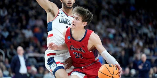 U-St. Mary's Aidan Mahaney (20) ushayela u-Nahiem Alleyne wase-Connecticut, kwesokunxele, engxenyeni yokuqala yomdlalo we-basketball wasekolishi womzuliswano wesibili ku-NCAA Tournament, ngeSonto, Mashi 19, 2023, e-Albany, NY