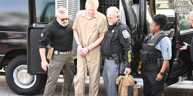 Alex Murdaugh is escorted into the courthouse wearing a tan prison jumpsuit.